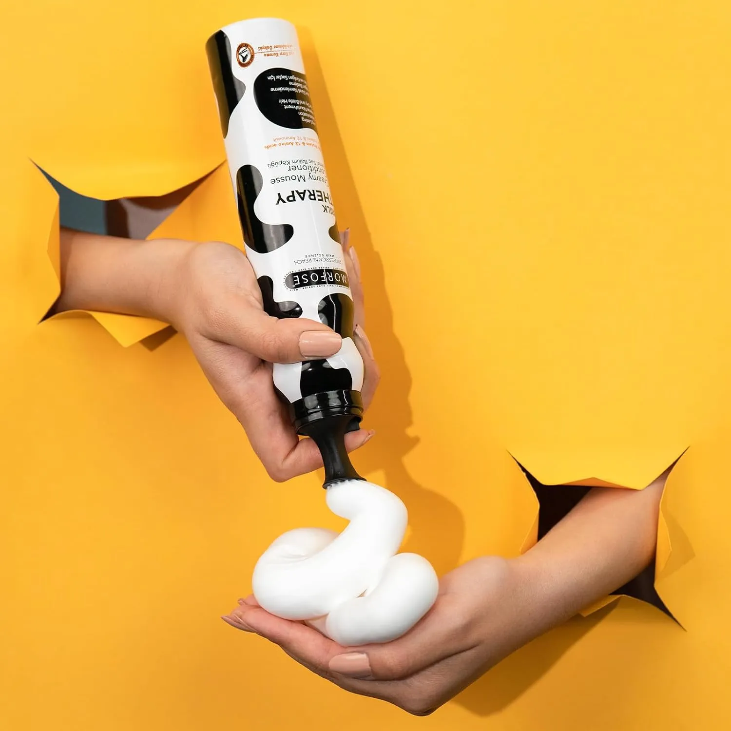 دست در حال پخش کردن موس سفید مورفوس مدل Milk Therapy از بطری روی کف دست