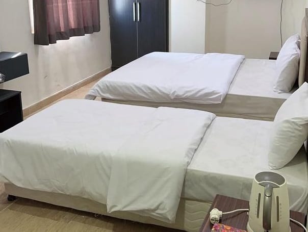 سوئیت چهارنفرهٔ هتل آپارتمان آدینه قشم با چند تخت و چای‌ساز