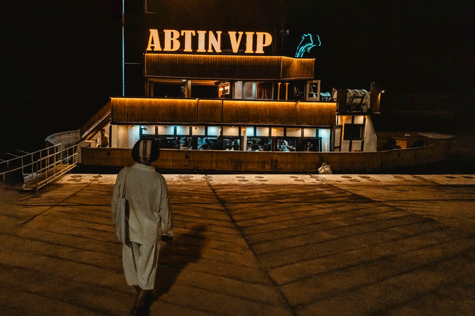 کشتی آبتین VIP پهلوگرفته در اسکلهٔ ابرکاوان قشم در شب با تابلوی نورانی و نئون دلفین