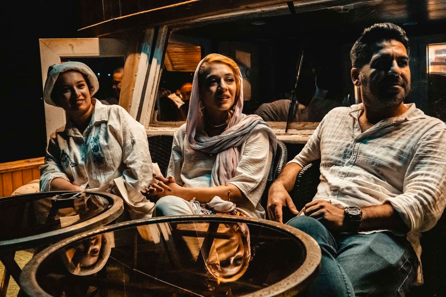 خانوادهٔ مسافر دور میز شیشه‌ای عرشهٔ کشتی آبتین قشم در گشت شبانه