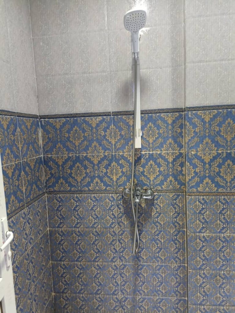 حمام با کاشی روشن و دوش در آپارتمان امپراطور قشم