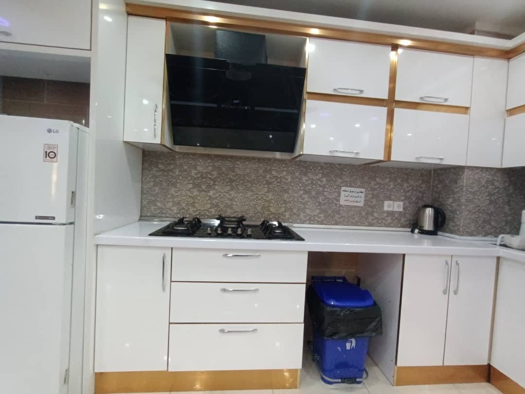 آشپزخانه با کابینت سفید و اجاق گاز در آپارتمان امپراطور ۴ قشم