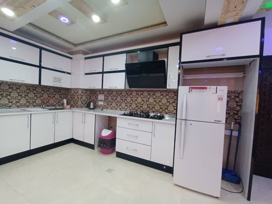 آشپزخانه با کابینت سفید و یخچال در آپارتمان امپراطور ۱ قشم