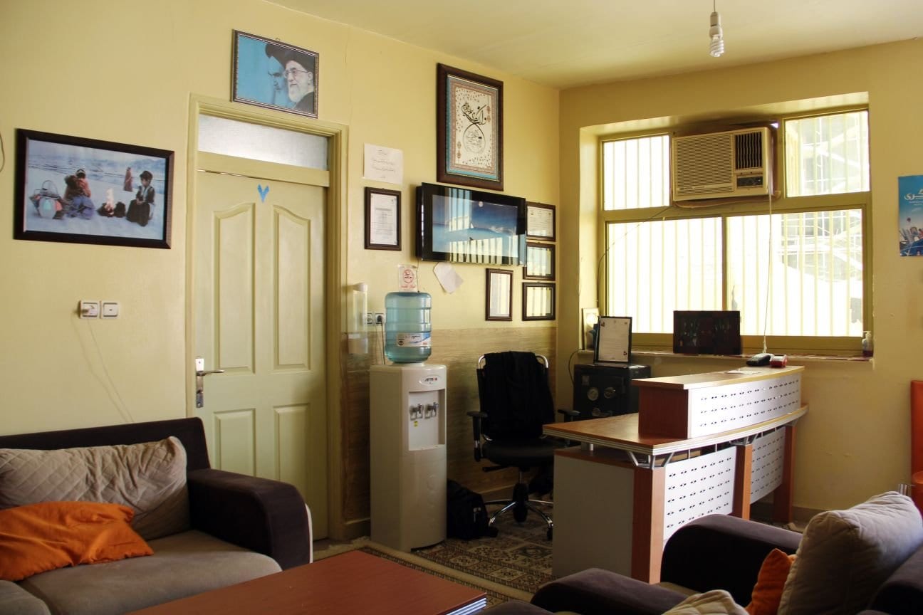 فضای پذیرش و دفتر مسافرخانه آیدین قشم با میز، آبسردکن و مبل