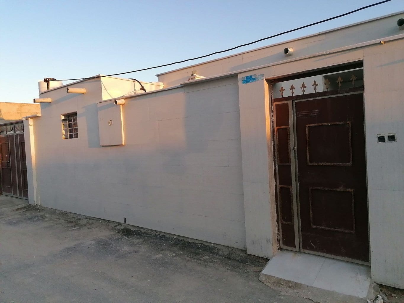 نمای بیرونی ساختمان یک‌طبقهٔ مجتمع توفان در درگهان قشم با درِ ورودی قهوه‌ای