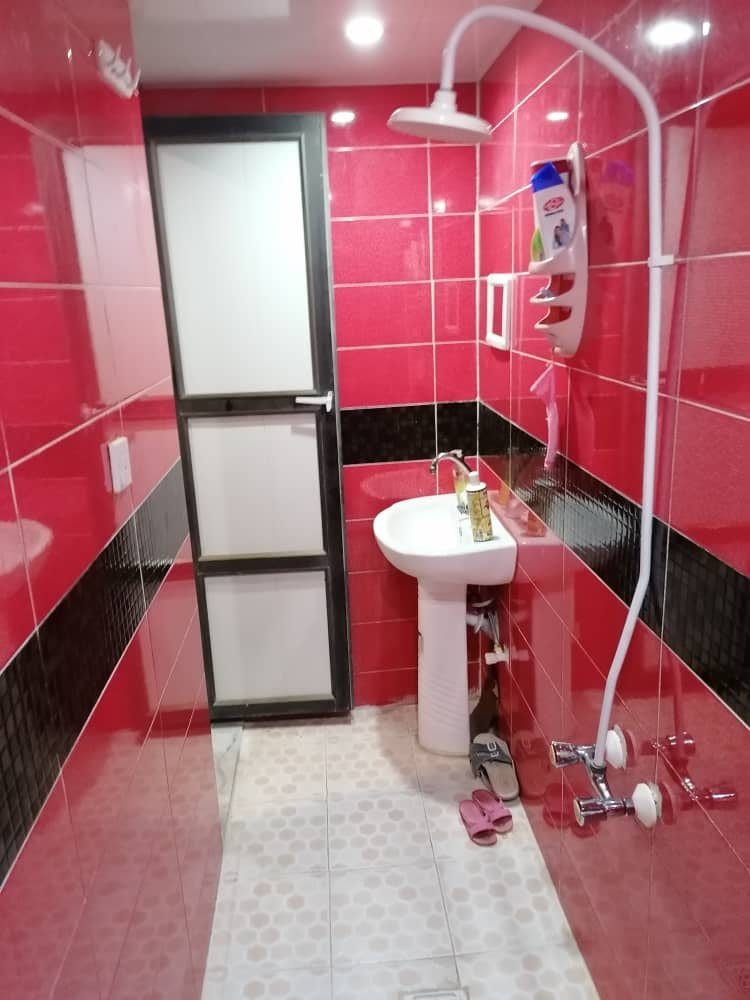حمام و دوش با کاشی‌کاری قرمز و روشویی در واحد ۴ مجتمع توفان درگهان قشم