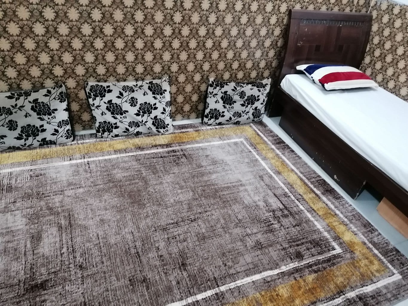 تخت یک‌نفره و رخت‌خواب سنتی روی فرش در واحد ۵ مجتمع توفان درگهان قشم