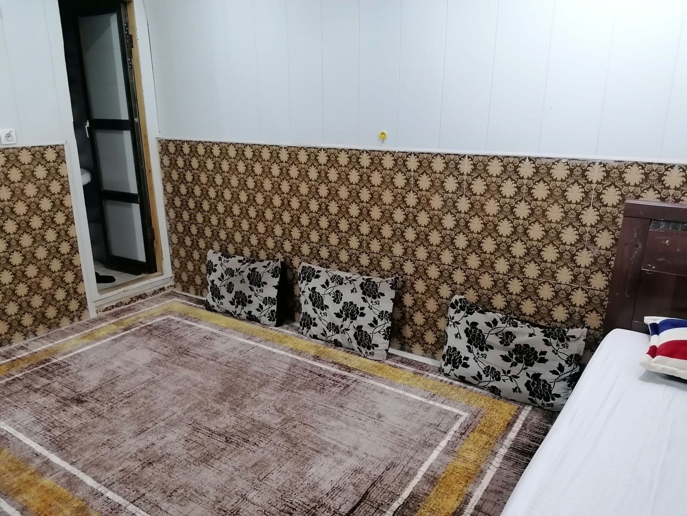 نمای اتاق با درِ ورودی سرویس بهداشتی و کوسن‌های نشیمن در سوئیت توفان قشم