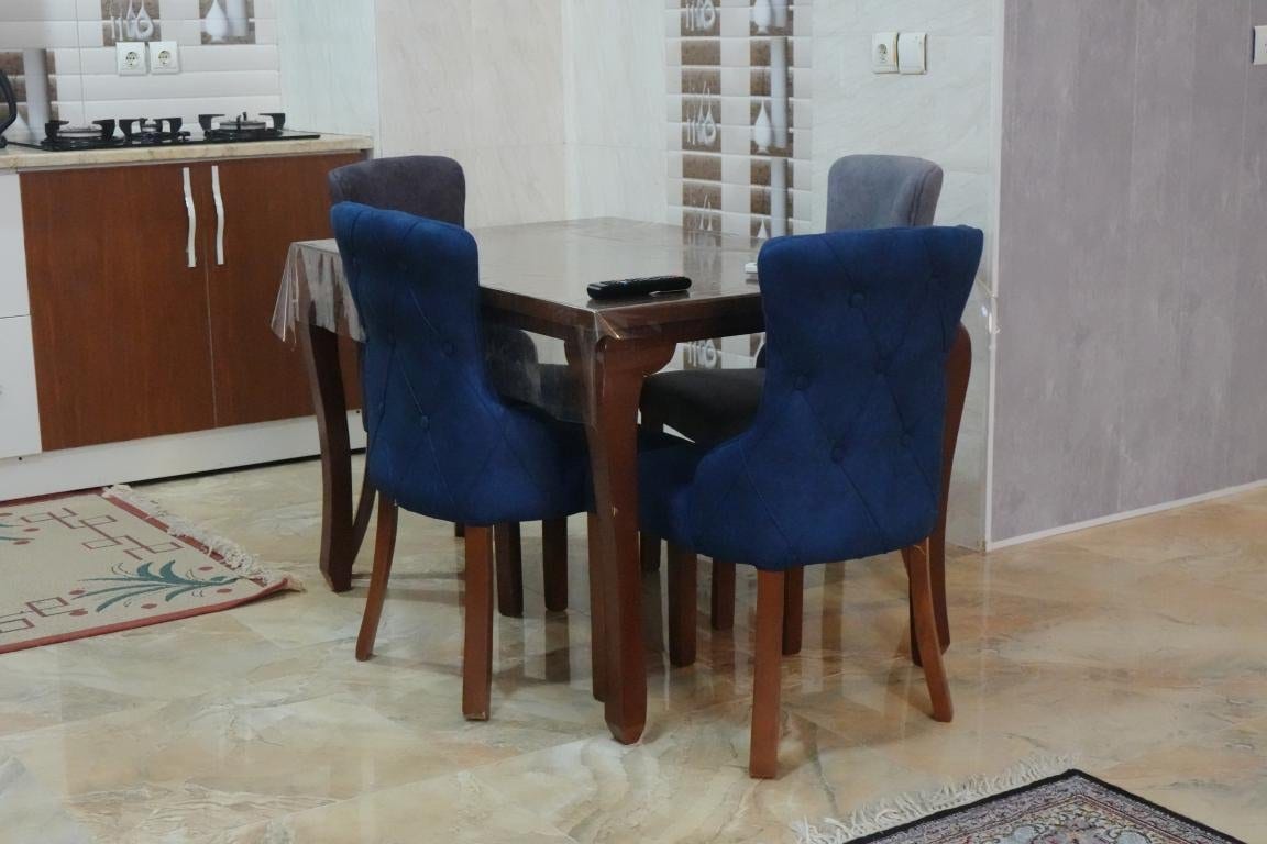 میز نهارخوری چهارنفره با صندلی‌های آبی در آپارتمان امید ممتاز واحد ۱۰۲ قشم