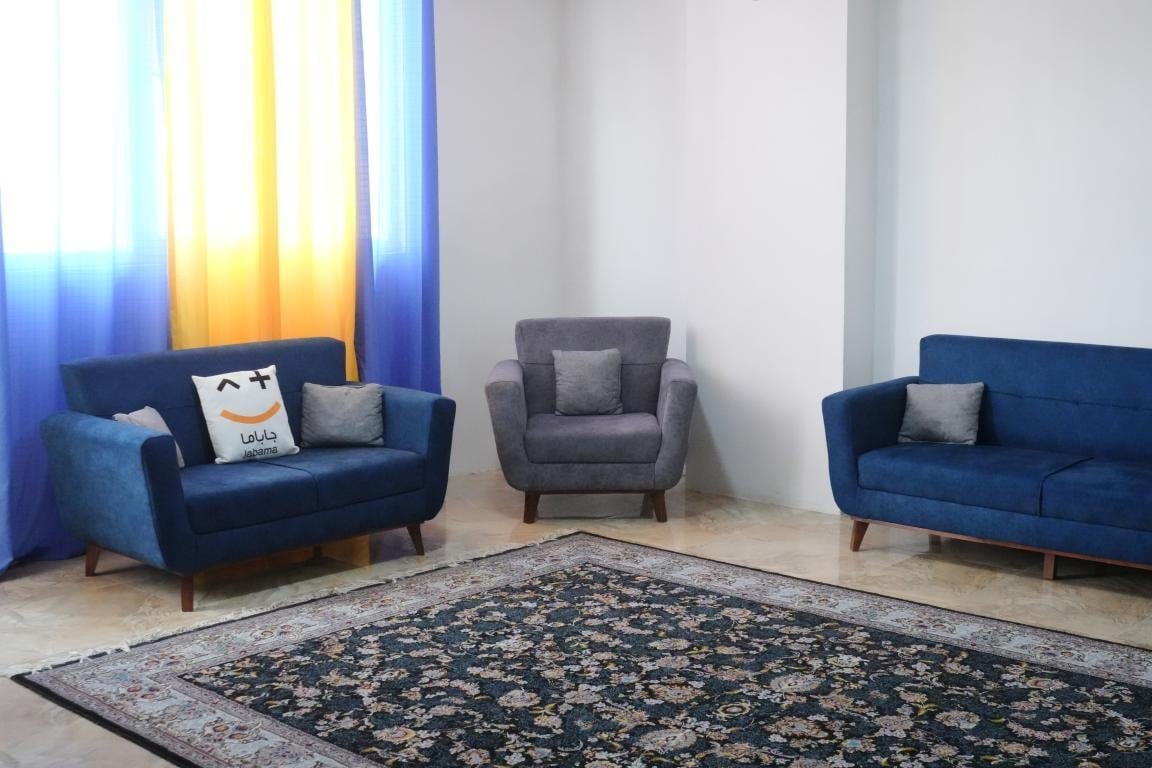 فضای پذیرایی با مبلمان طوسی و آبی در آپارتمان امید ممتاز واحد ۱۰۲ قشم