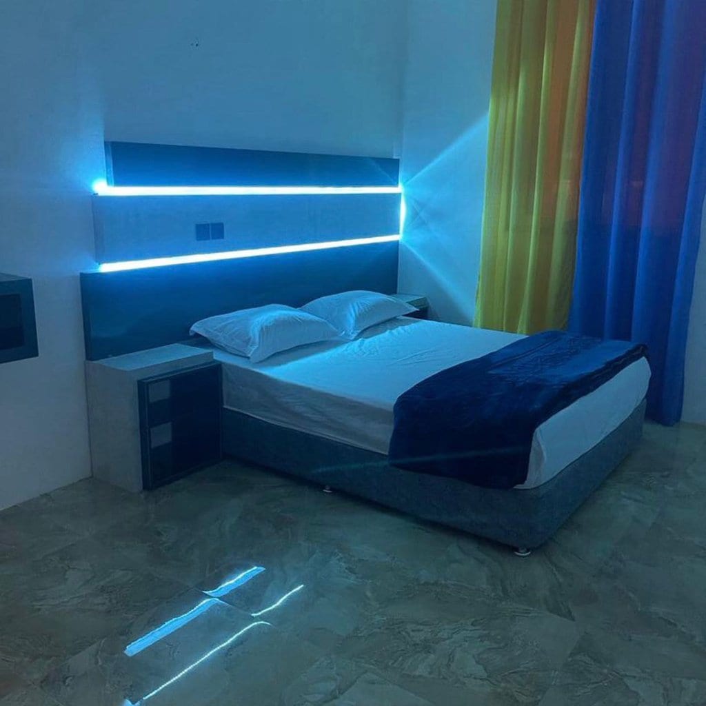 اتاق‌خواب با تخت دونفره و نورپردازی LED و پردهٔ زرد در آپارتمان آبی قشم