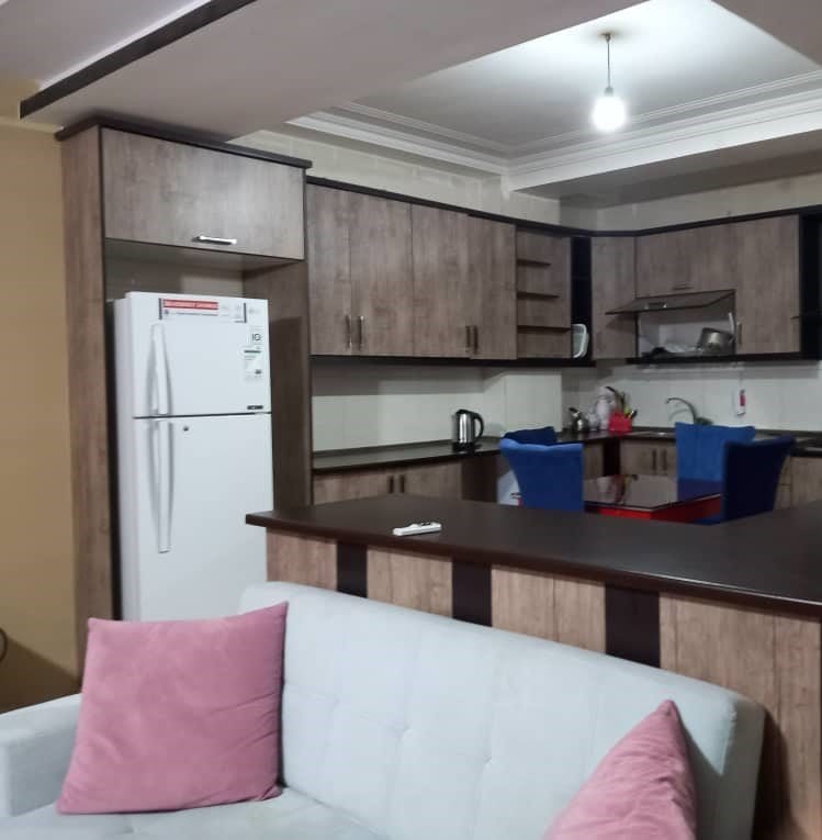 آشپزخانه با کابینت، یخچال و میز نهارخوری در آپارتمان ۱۲۰متری خانوادگی قشم