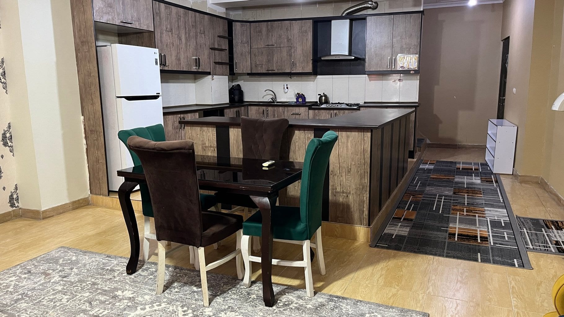 سالن پذیرایی با صندلی راحتی سبز و فرش دستباف در آپارتمان ۱۲۰متری قشم