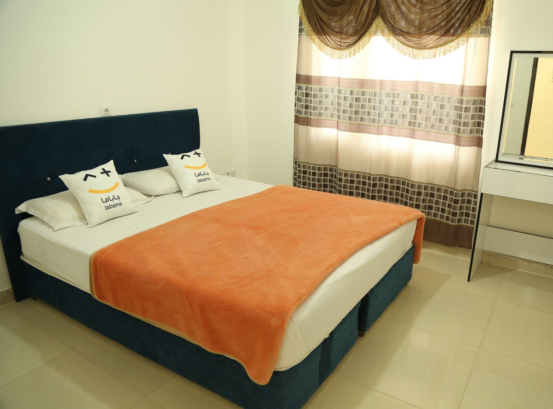 اتاق‌خواب با تخت دونفره و روتختی نارنجی در آپارتمان اقتصادی قشم