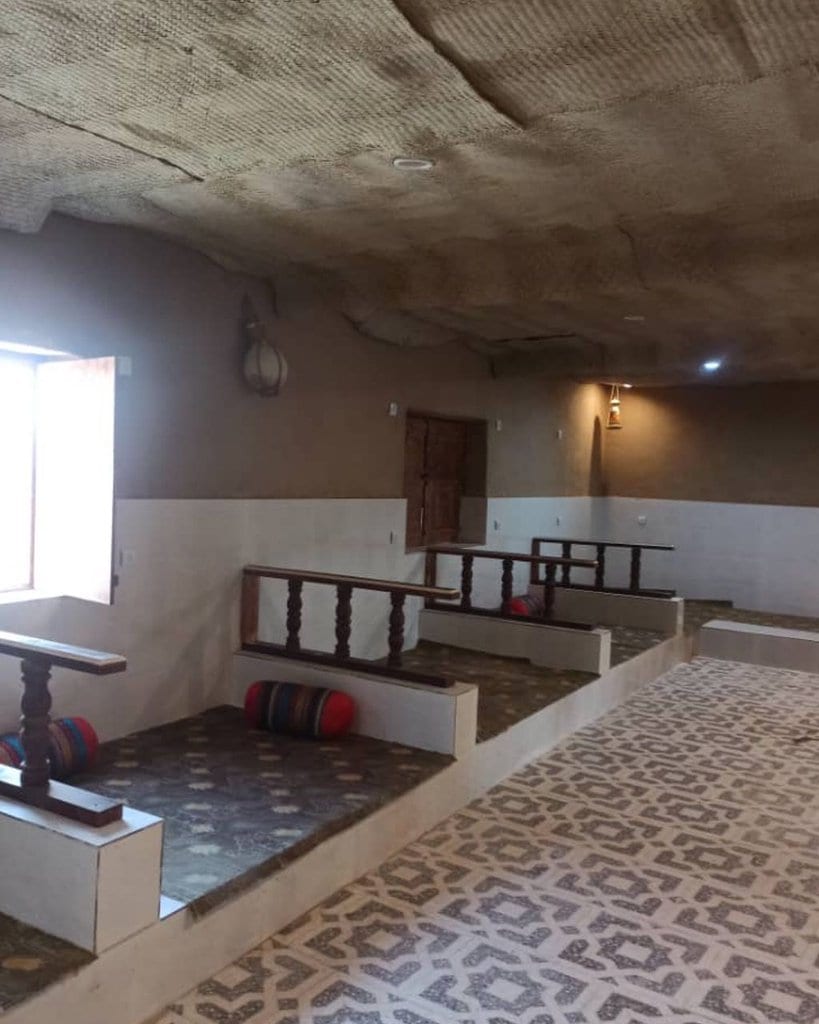 اتاق با کفپوش سبز و نشیمن سنتی در بوم‌گردی چیرا قشم