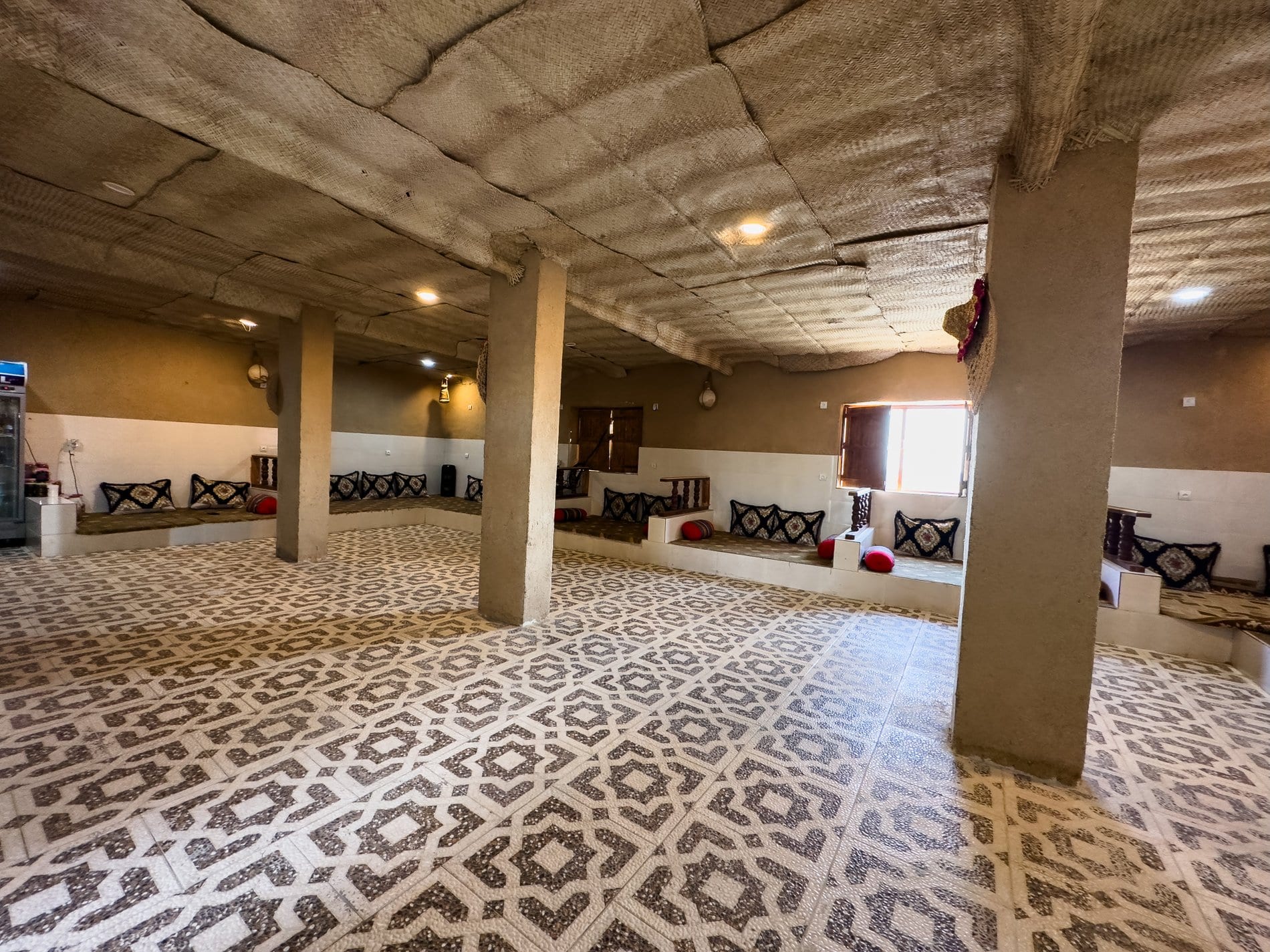 تالار سنتی بزرگ با کفپوش طرح‌دار و نشیمن کناری در بوم‌گردی چیرا قشم