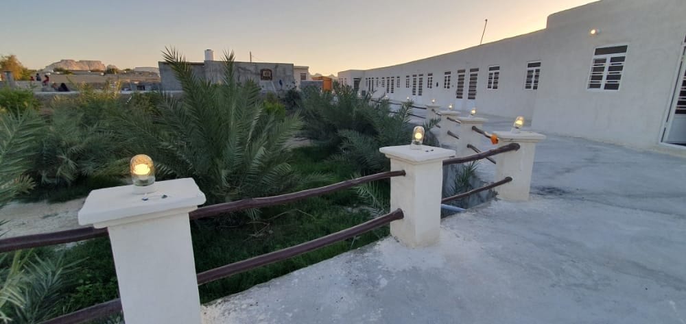 طاقِ قوسیِ سفید و نخلِ محوطه در حیاطِ بوم‌گردی مالوک قشم