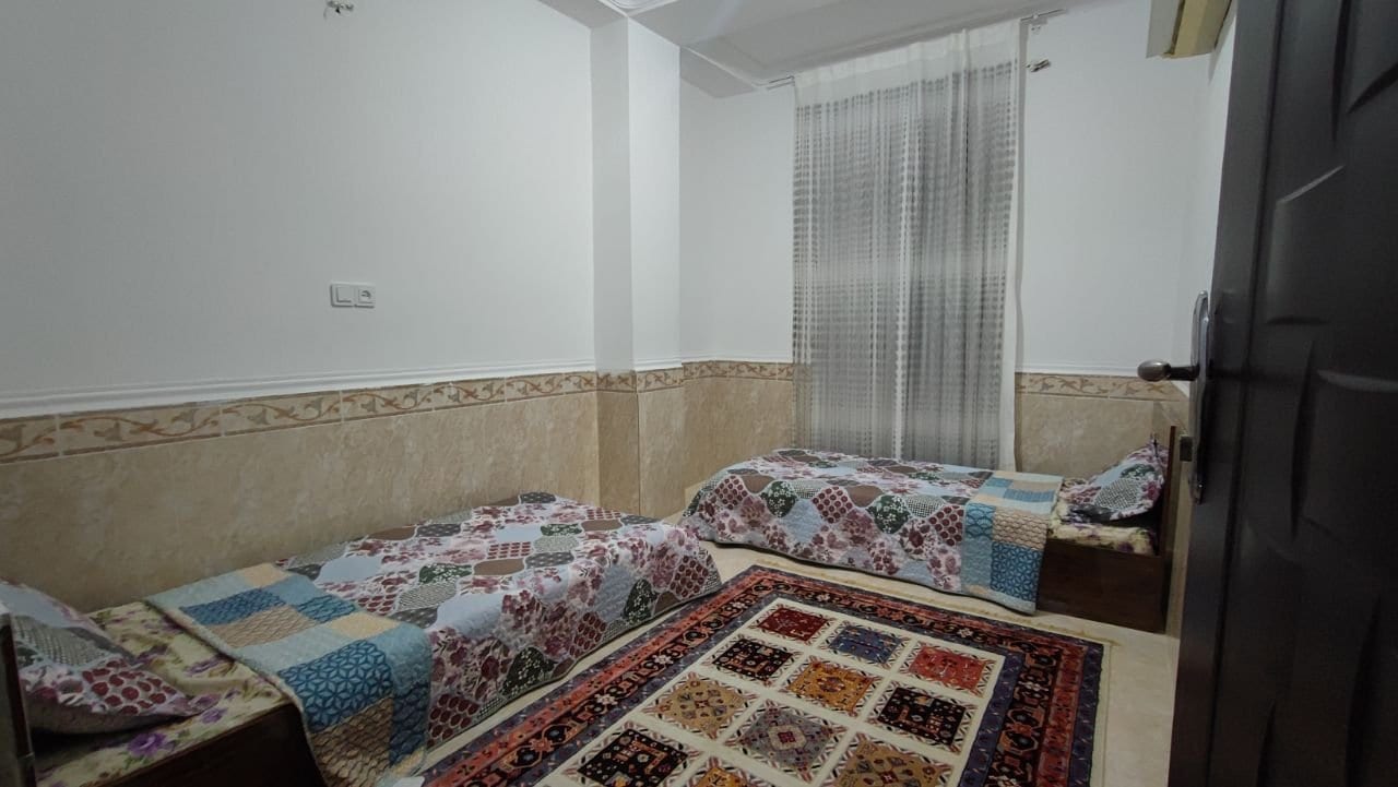 اتاق‌خواب با چند تخت و روتختی چهل‌تکه در آپارتمان خانوادگی قشم