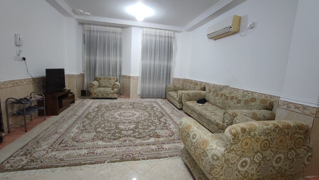 نشیمن با مبل راحتی گل‌دار و تلویزیون در آپارتمان خانوادگی قشم