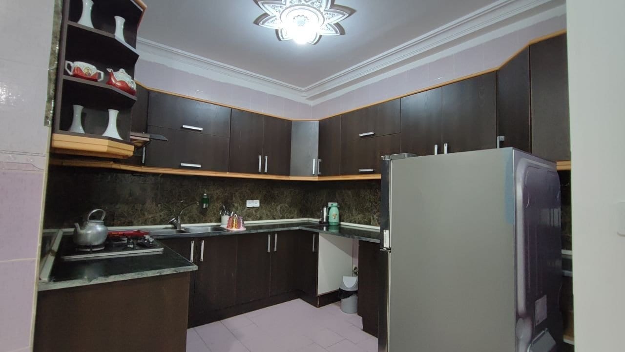 آشپزخانه با کابینت قهوه‌ای، یخچال و اجاق گاز در آپارتمان قشم