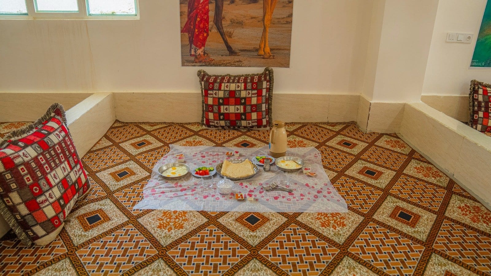 سفرهٔ سنتی و نشیمن روی تخت چوبی با پشتی در بوم‌گردی میرزا واحد ۱۳ قشم