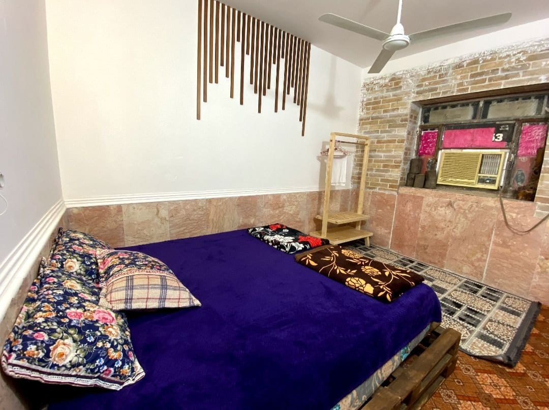 اتاق‌خواب با تخت دونفره و روتختیِ بنفش در ویلا ساحلی حسین هرمز