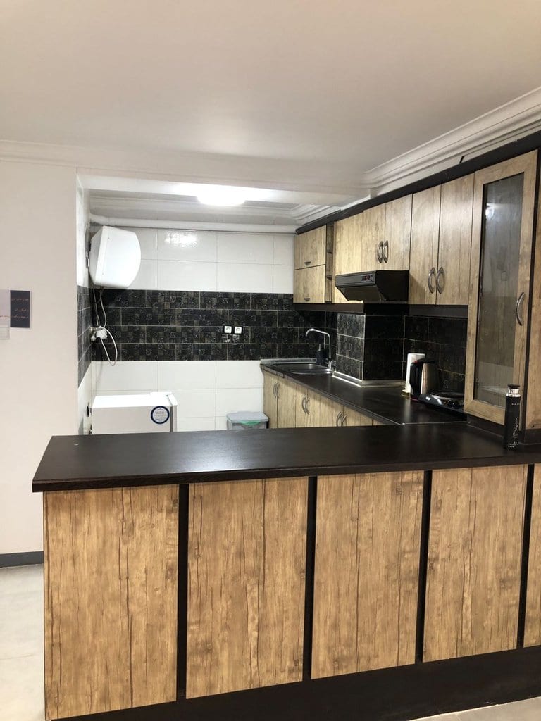 آشپزخانه با کابینت چوبی، آب‌گرمکن و اجاق گاز در سوئیت آرامون قشم
