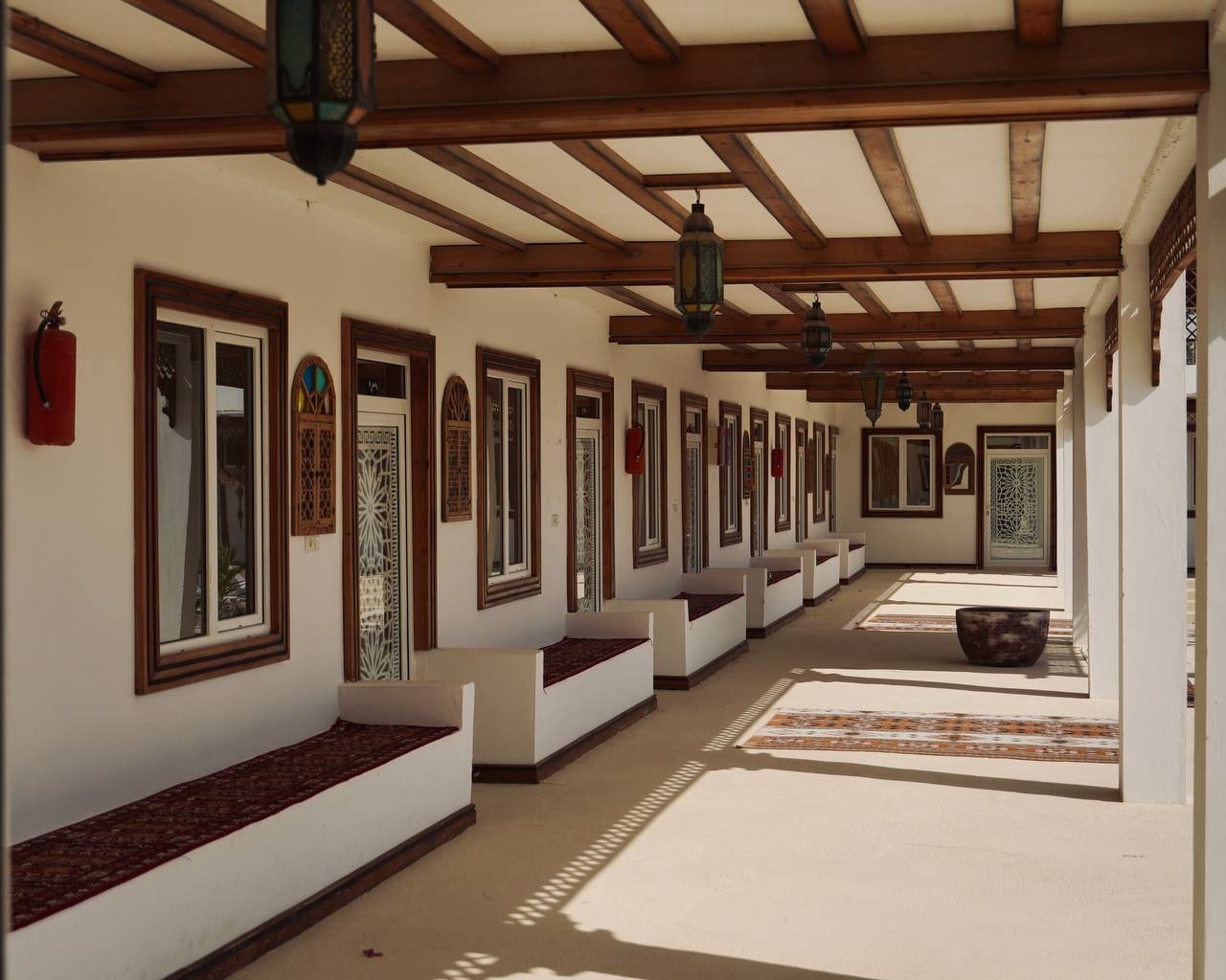 راهروی سرپوشیده با لوسترها و قاب‌های دیواری در اقامتگاه زرین قشم