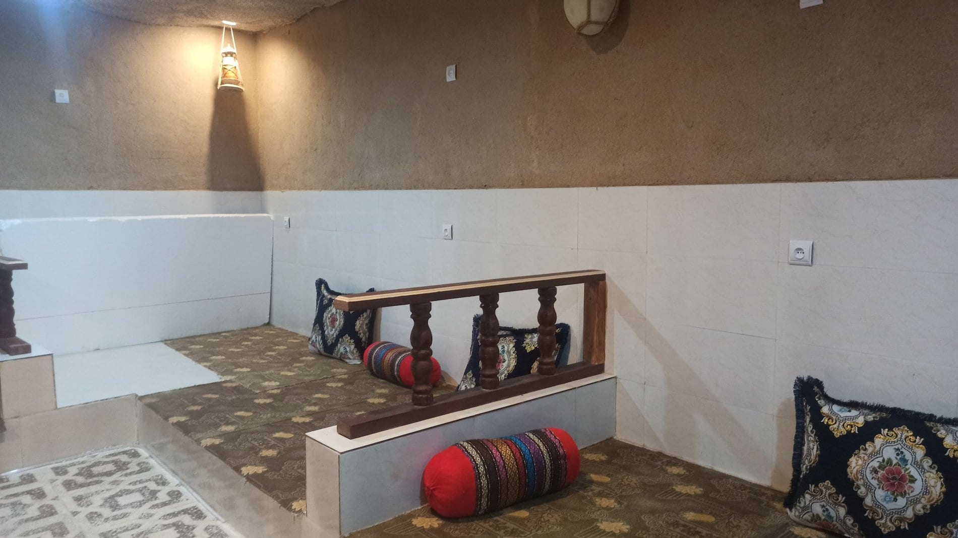 نشیمن با تخت چوبی سنتی و پشتی در بوم‌گردی چیرا واحد گنبدی قشم