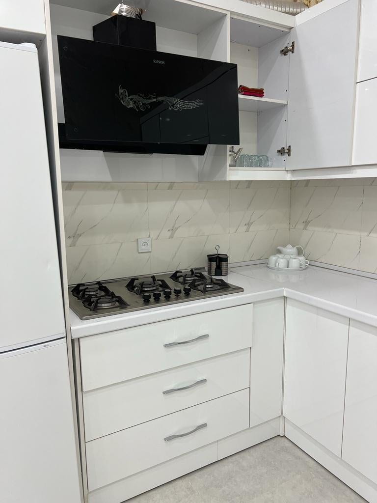 آشپزخانه با کابینت سفید، اجاق گاز و تلویزیون در ویلای کلودنگ هرمز