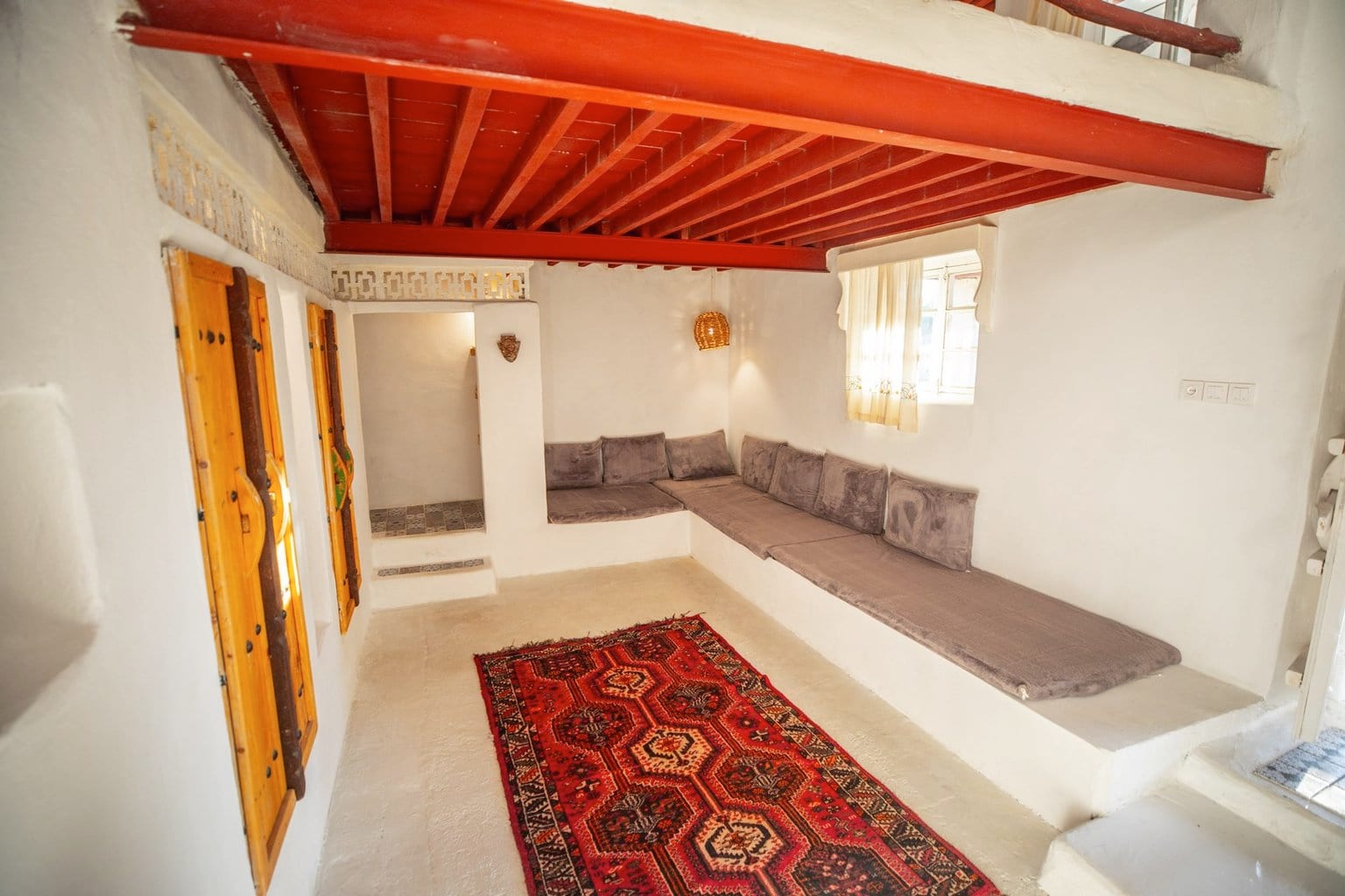 نشیمنِ دل‌باز با منظره به محوطه و سقفِ چوبی در بوم‌گردی هفت رنگو قشم