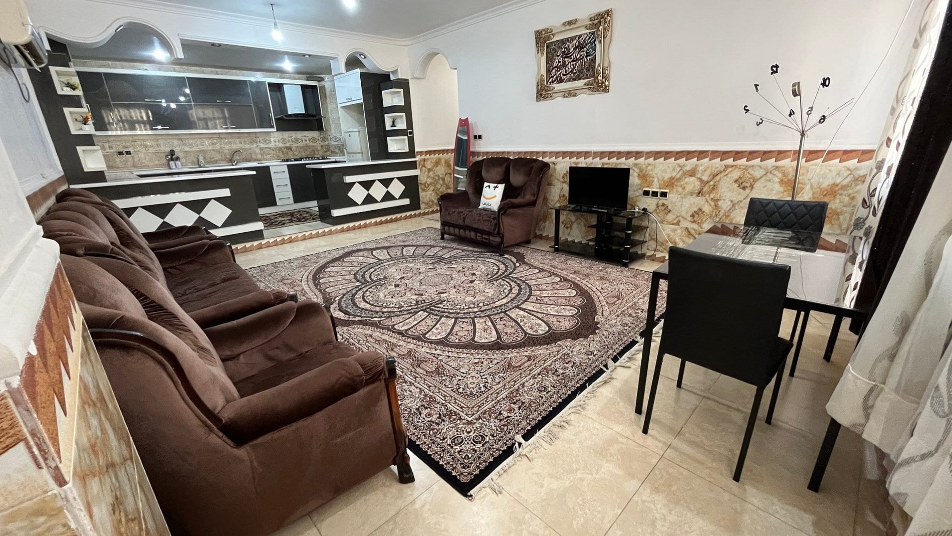 نشیمن مبله با فرش گردِ طرح‌دار در آپارتمان دوخوابه مرکز شهر قشم