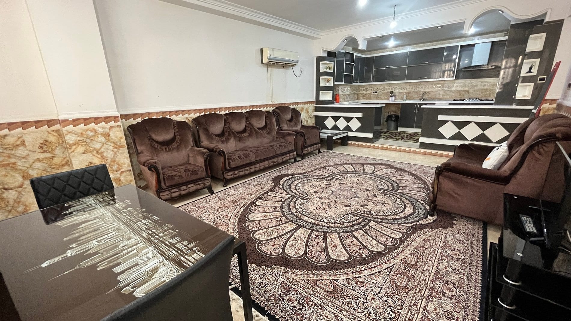 نشیمن مبله با فرش طرح‌دار در آپارتمان دوخوابه مرکز شهر قشم