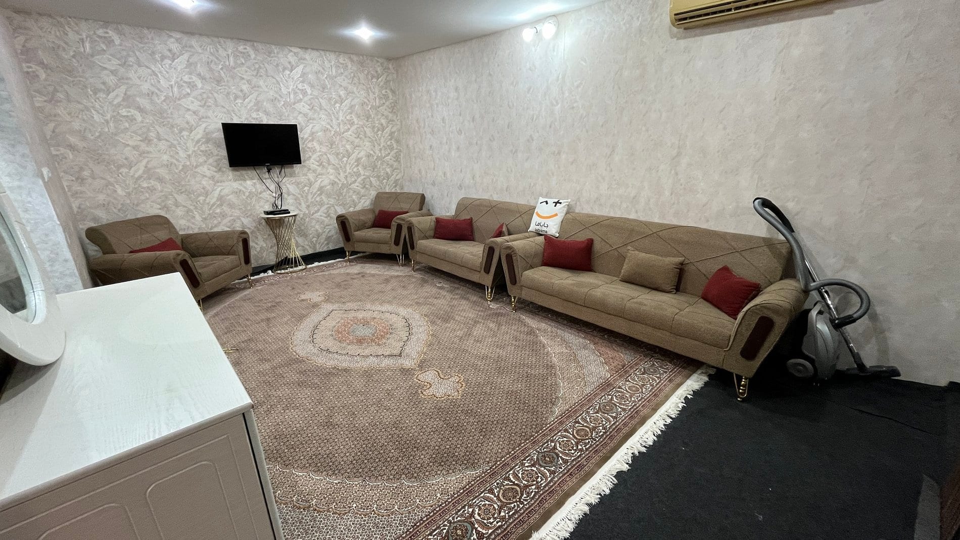 نشیمن مبله با مبل‌های راحتی و فرش گرد در آپارتمان ۶۰متری قشم