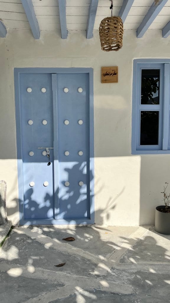 درِ آبی واحد گُرُمزَنگی با تابلوی نام واحد در بوم‌گردی گل ابریشم قشم