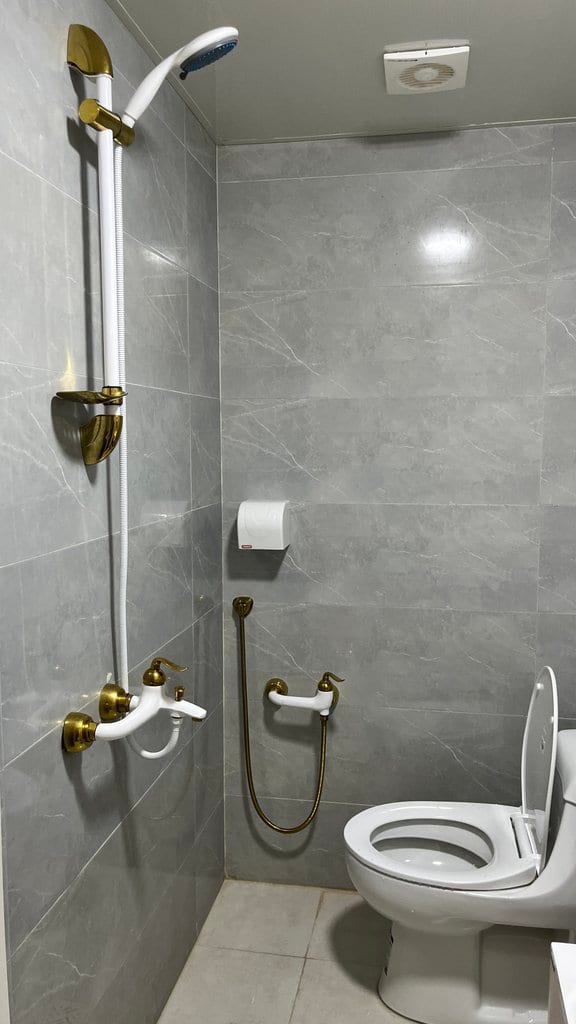جزئیات دوش و شیرآلات حمام با کاشی خاکستری در بوم‌گردی گل ابریشم قشم