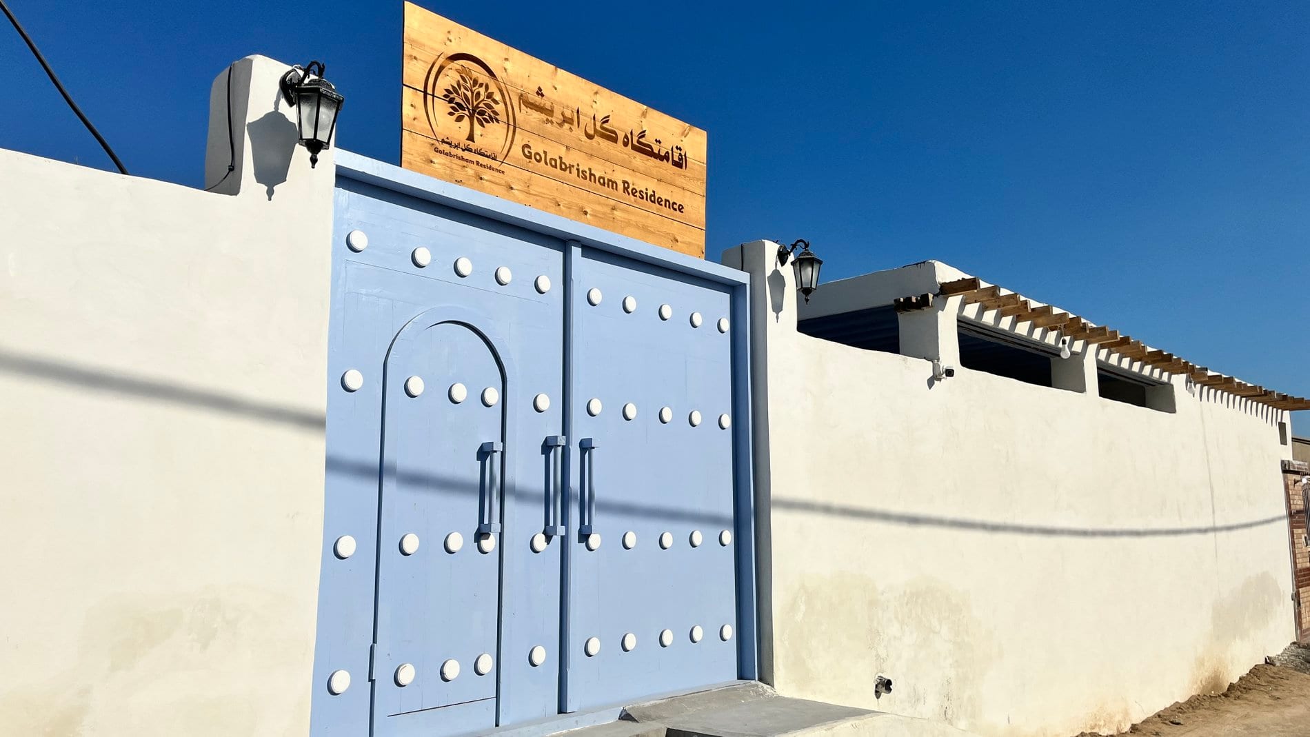 درِ ورودیِ آبی و تابلوی «اقامتگاه گل ابریشم / Golabrisham Residence» در قشم