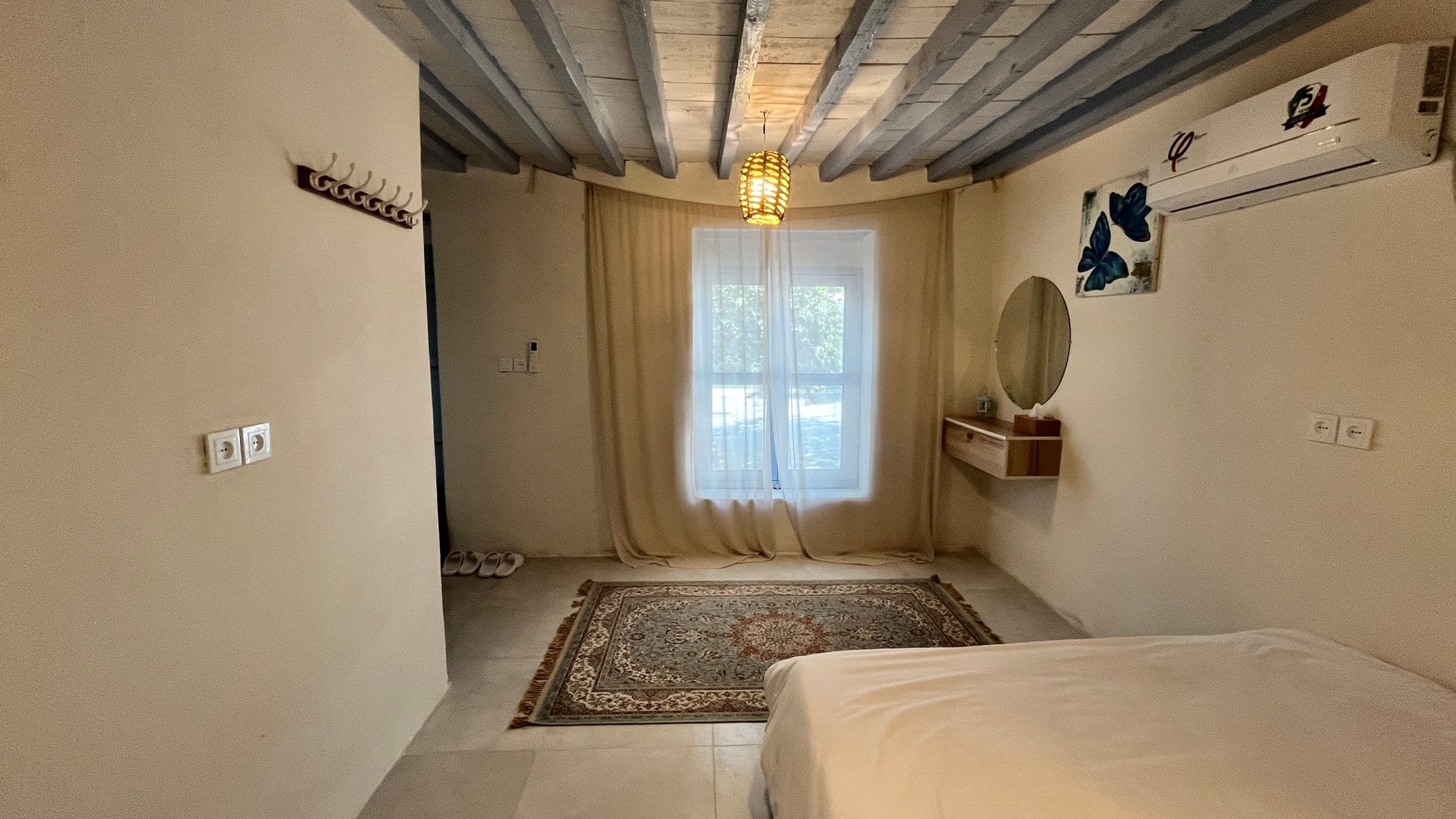 اتاق‌خواب با تخت دونفره، سقف تیرچوبی، پرده و فرش در واحد زیتون بوم‌گردی گل ابریشم قشم