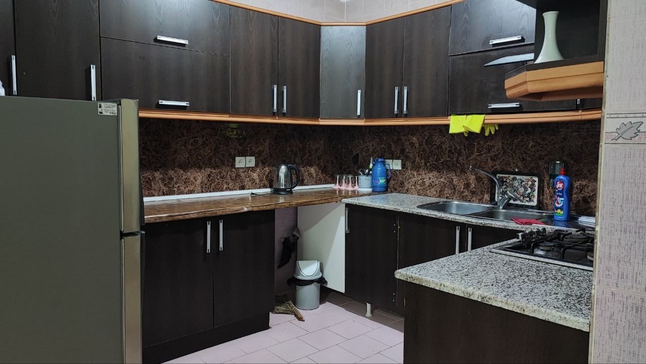 آشپزخانه با کابینت قهوه‌ای، یخچال و اجاق گاز در آپارتمان قشم