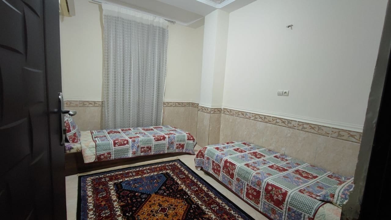 اتاق‌خواب با تخت دونفره و کفپوش فرش در آپارتمان دنج قشم