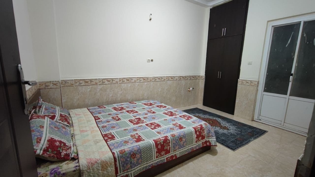 اتاق‌خواب با تخت و روتختی گلدار در آپارتمان دوخوابه قشم