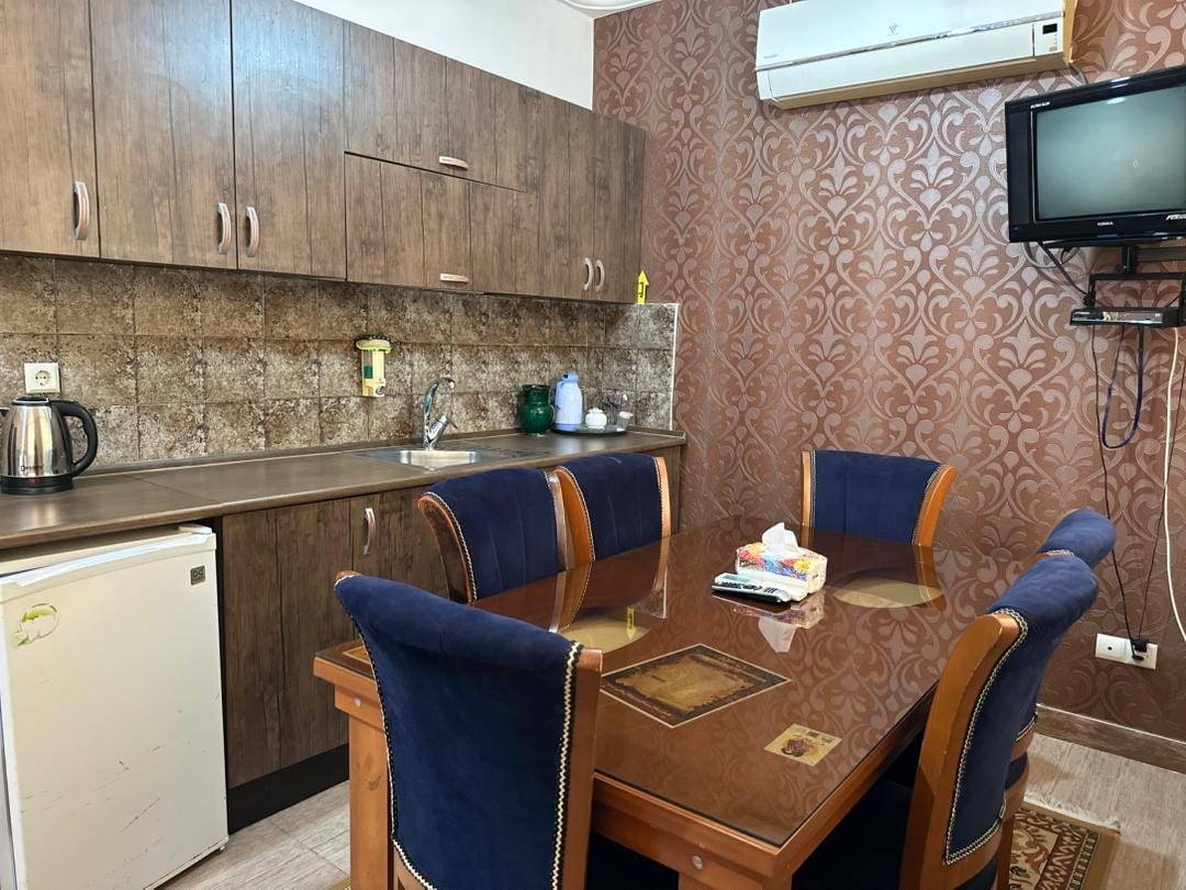میز نهارخوری چهارنفره و آشپزخانه با تلویزیون دیواری در واحد پونه قشم