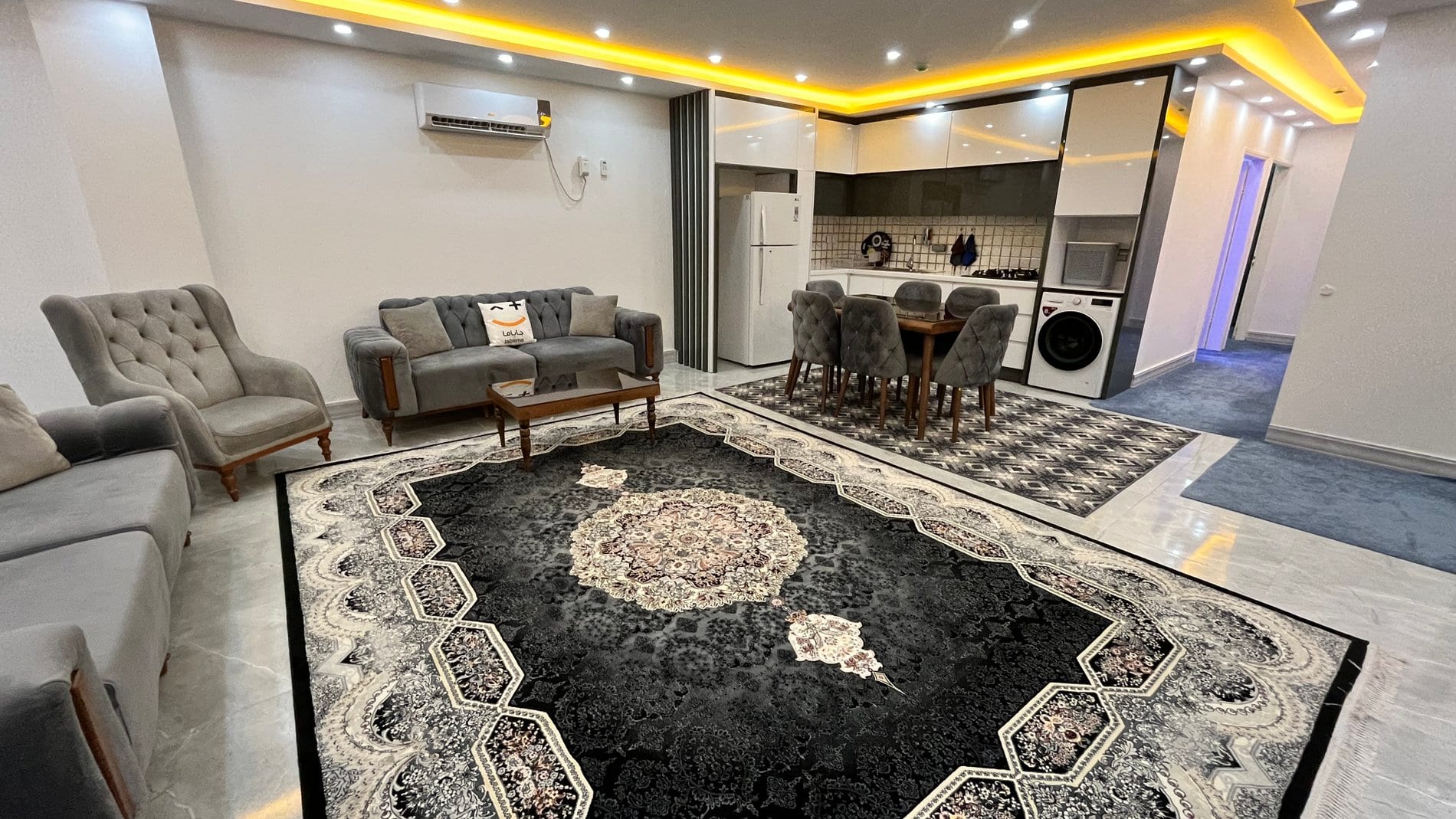 نشیمن و ناهارخوری با مبلمان طوسی در آپارتمان سه‌خوابه قشم