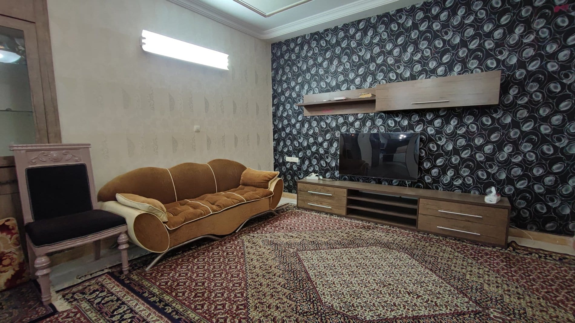 نشیمن مفروش با مبل و تلویزیون دیواری در ویلای سنتی قشم