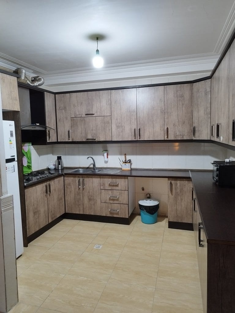 آشپزخانه با کابینت چوبی و یخچال در آپارتمان امید ۱ واحد ۱۲ قشم