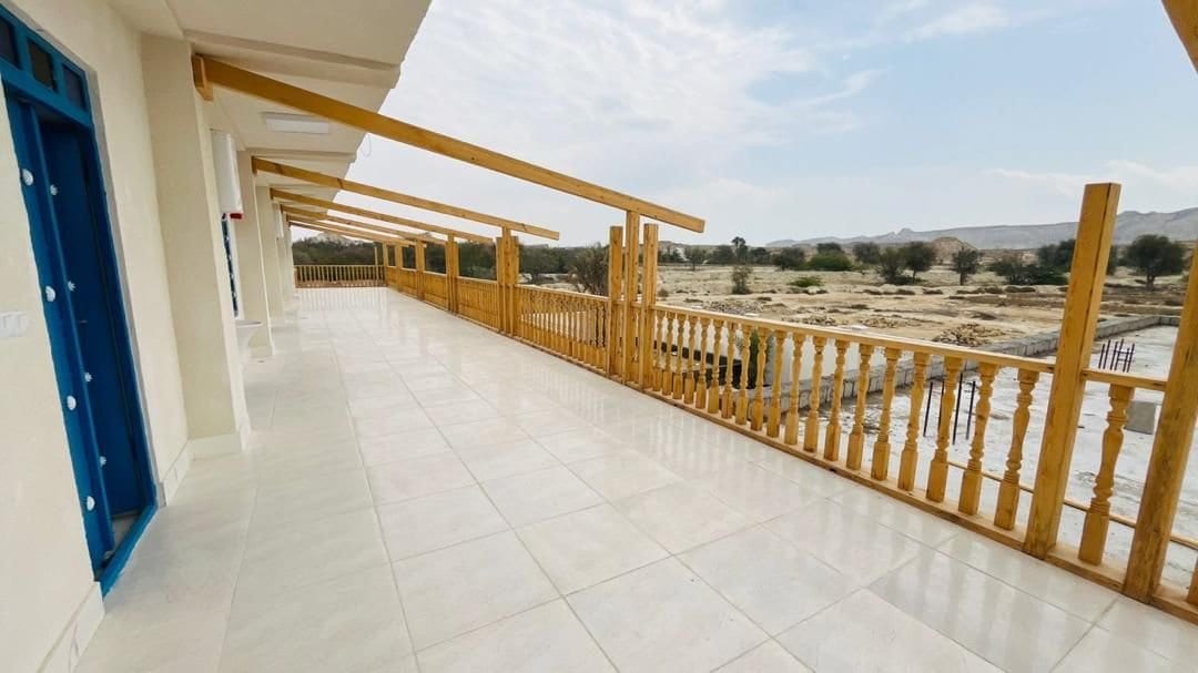 تراس و بالکن چوبی طبقهٔ بالا با نرده و دید به محوطه در بوم‌گردی ناخدا عبدالصالح قشم