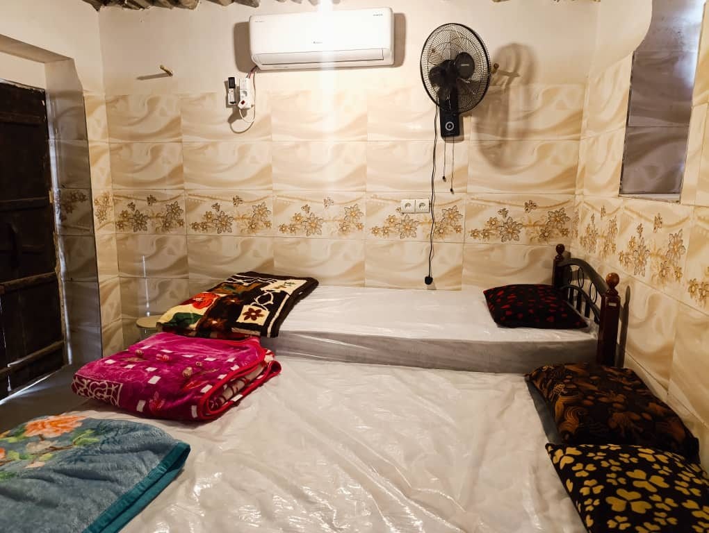 اتاق سنتی با رخت‌خواب محلی و دیوار گچیِ سفید در واحد قلعه بوم‌گردی ناخدا علی قشم