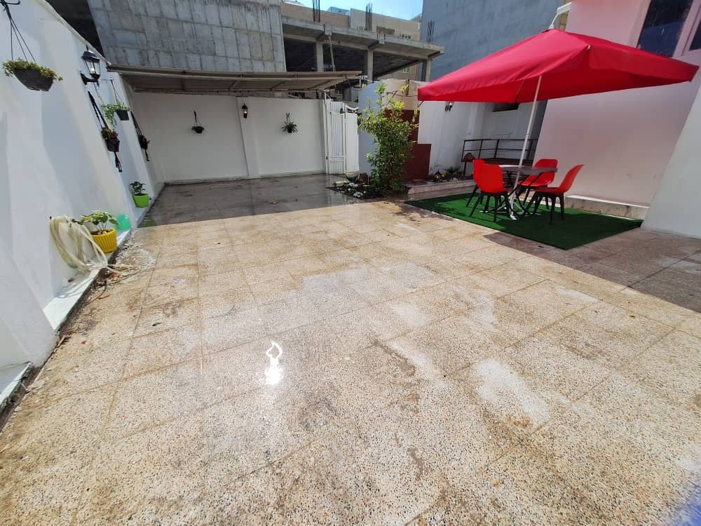 حیاطِ نشیمن‌دار با چترِ قرمز در ویلا عمارت ۳ قشم