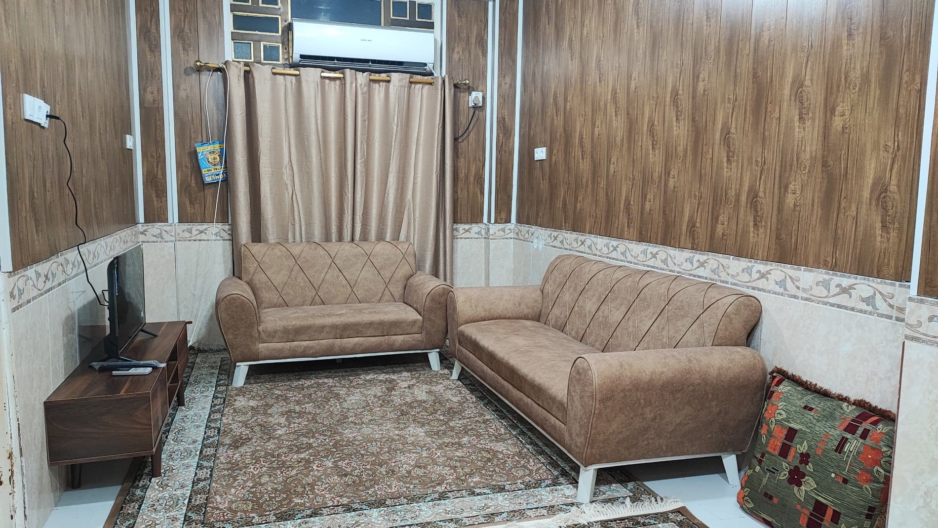 ست مبل بژ پذیرایی روی فرش در آپارتمان یک‌خوابه دانشمند ۳ قشم