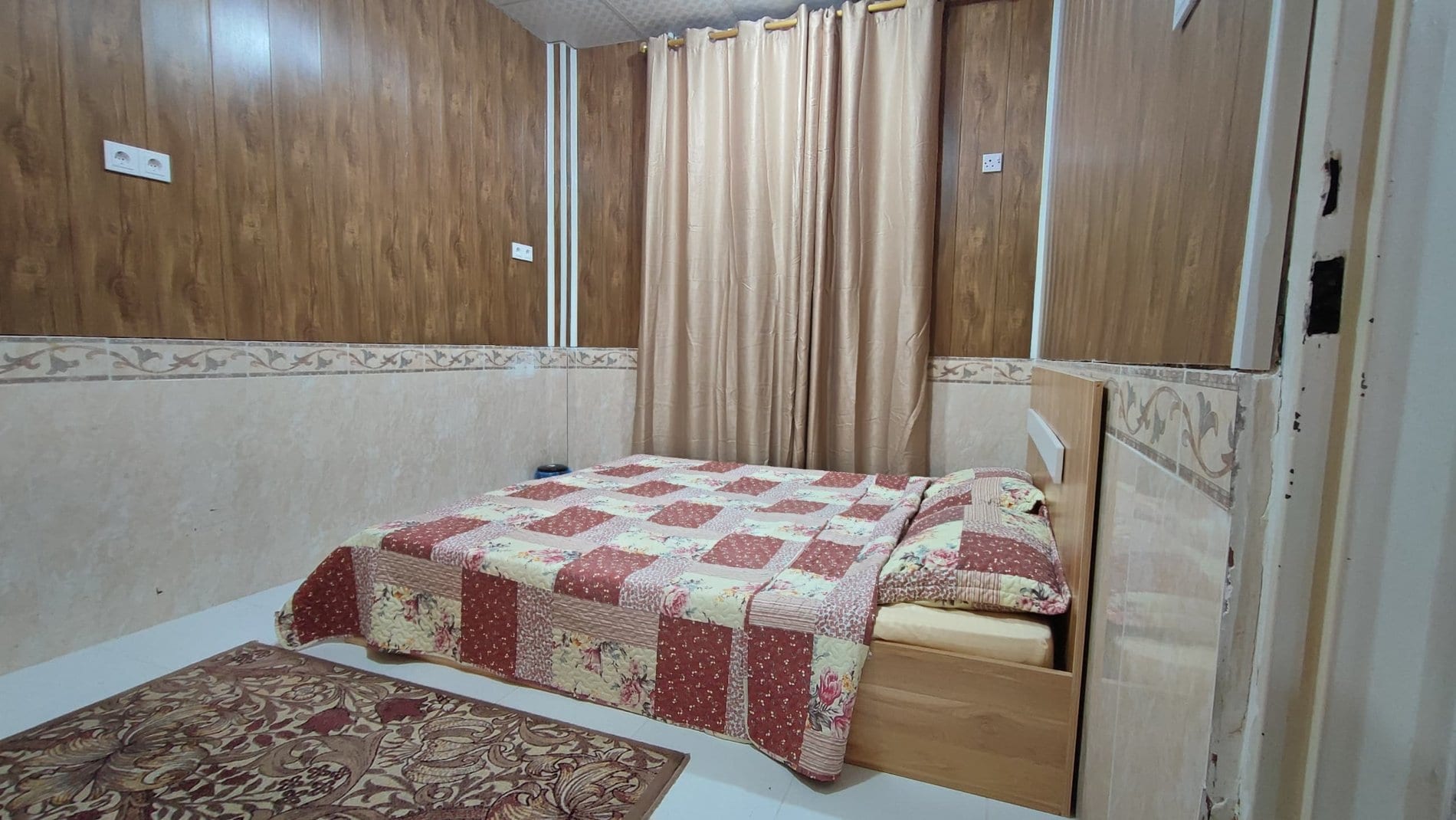 اتاق‌خواب با روتختی قرمز شطرنجی در آپارتمان یک‌خوابه دانشمند ۳ قشم